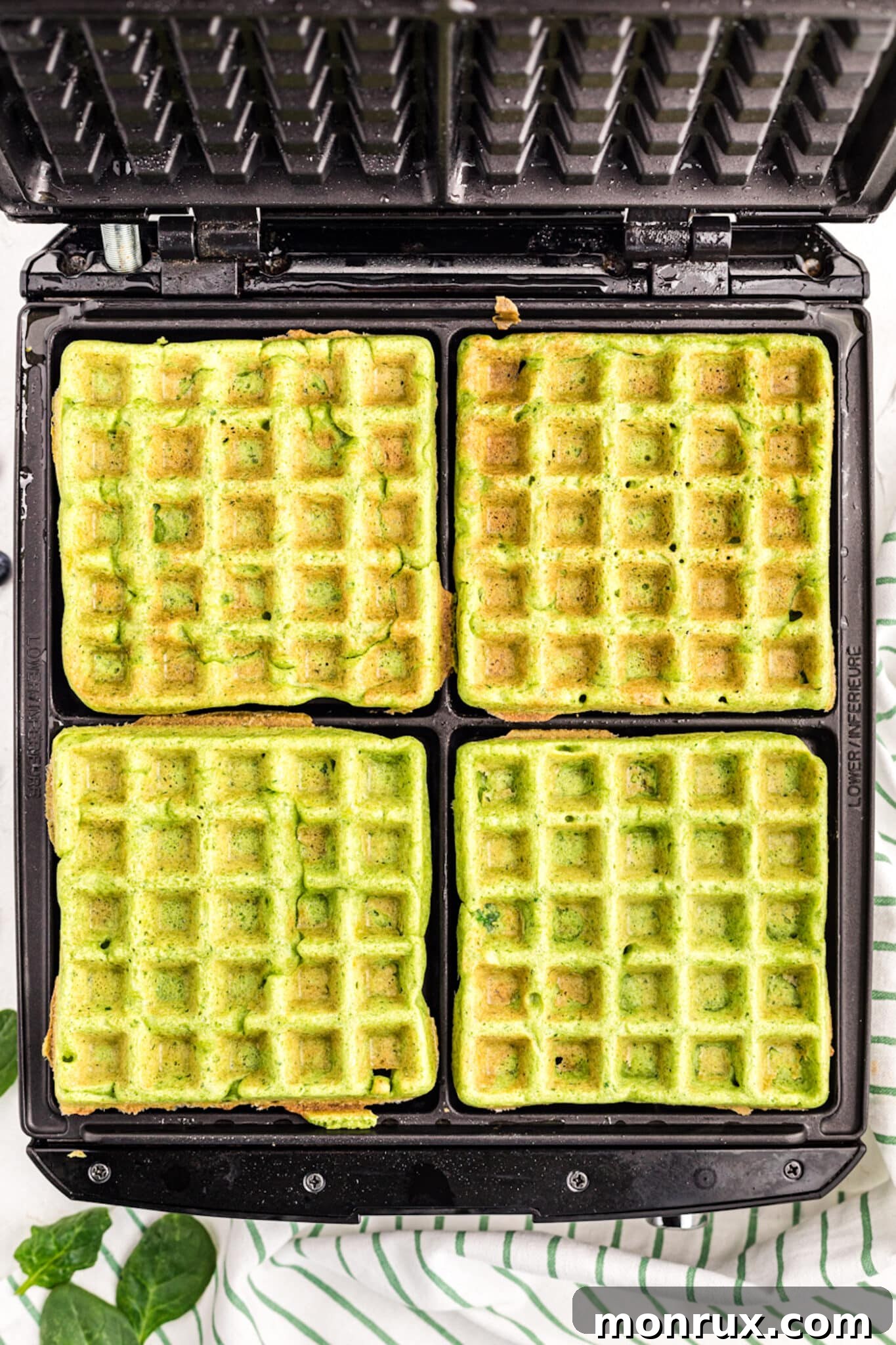 A stack of freshly cooked, golden-brown green waffles.