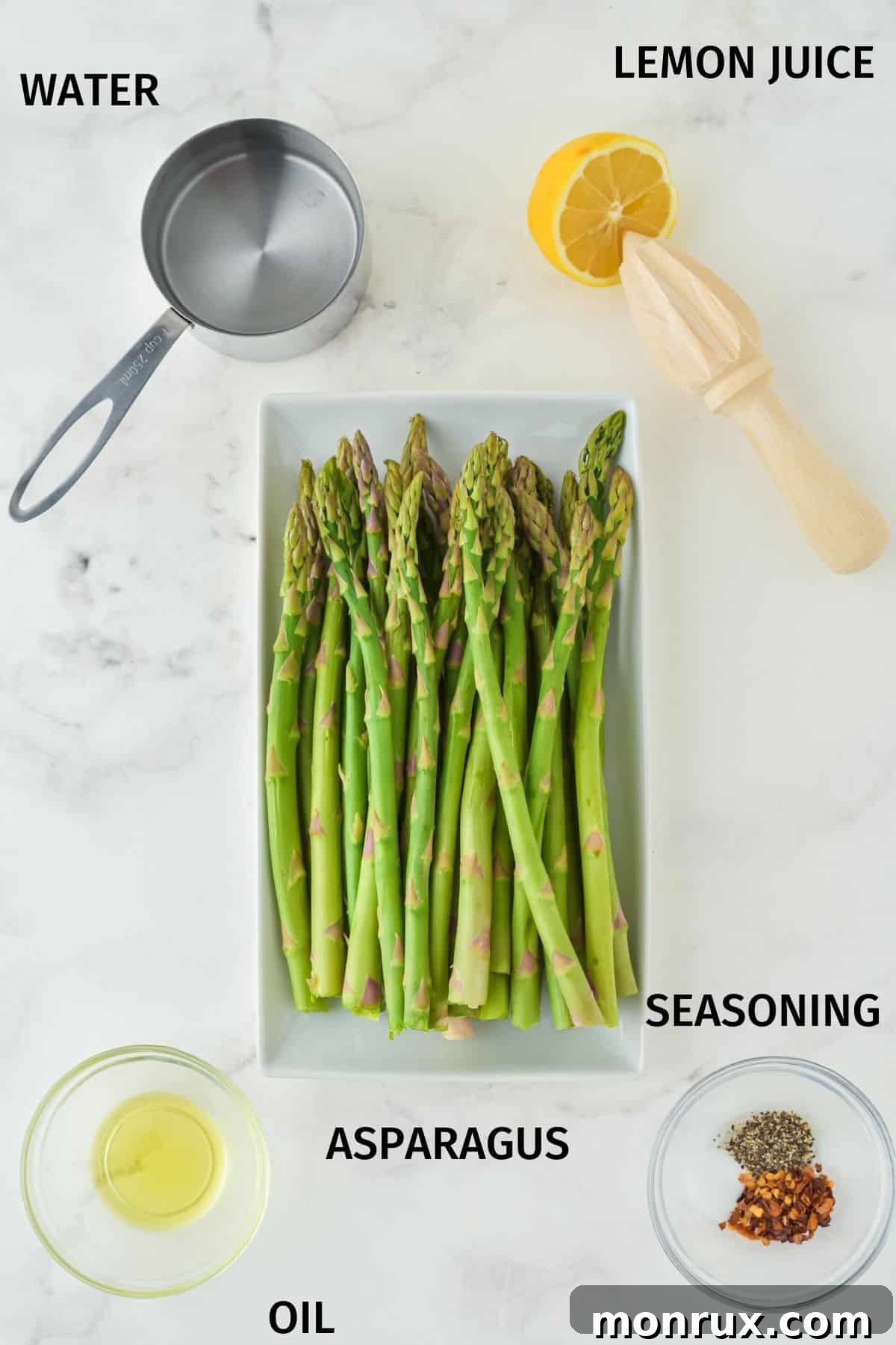 Ingredients for Instant Pot asparagus on a white surface, including fresh asparagus spears, a lemon, olive oil, and chili flakes.