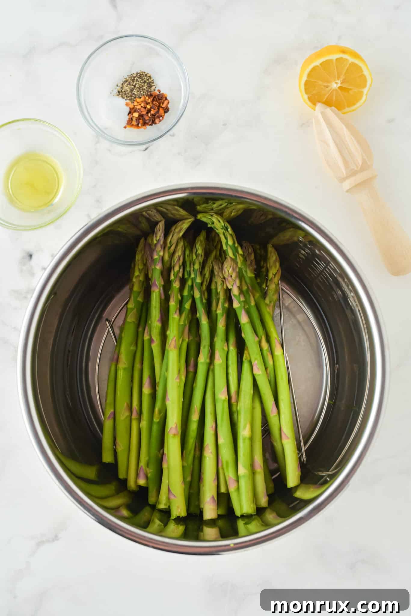 Fresh asparagus spears neatly arranged on a trivet inside an Instant Pot insert, ready for cooking.