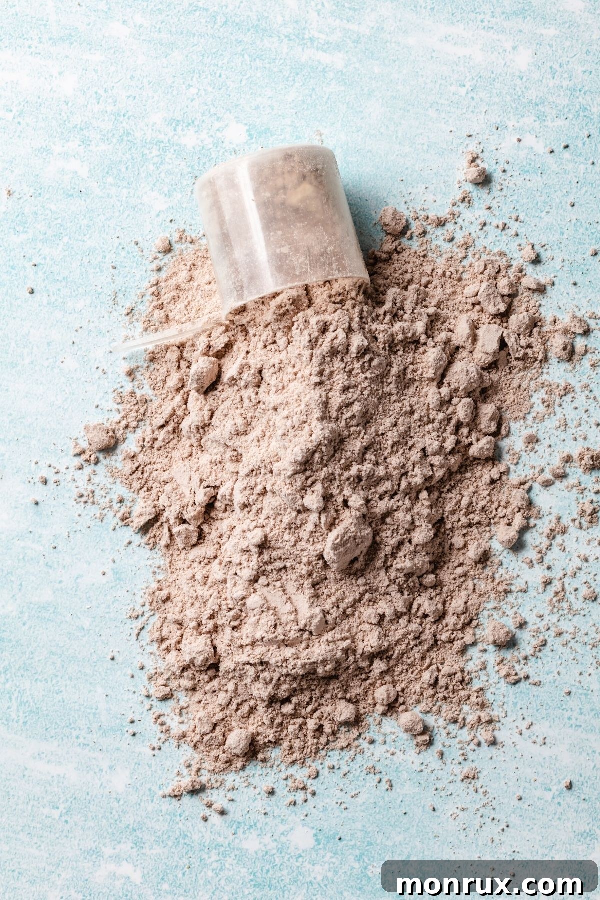 A scoop of golden-brown cricket protein powder on a surface, emphasizing its fine texture.