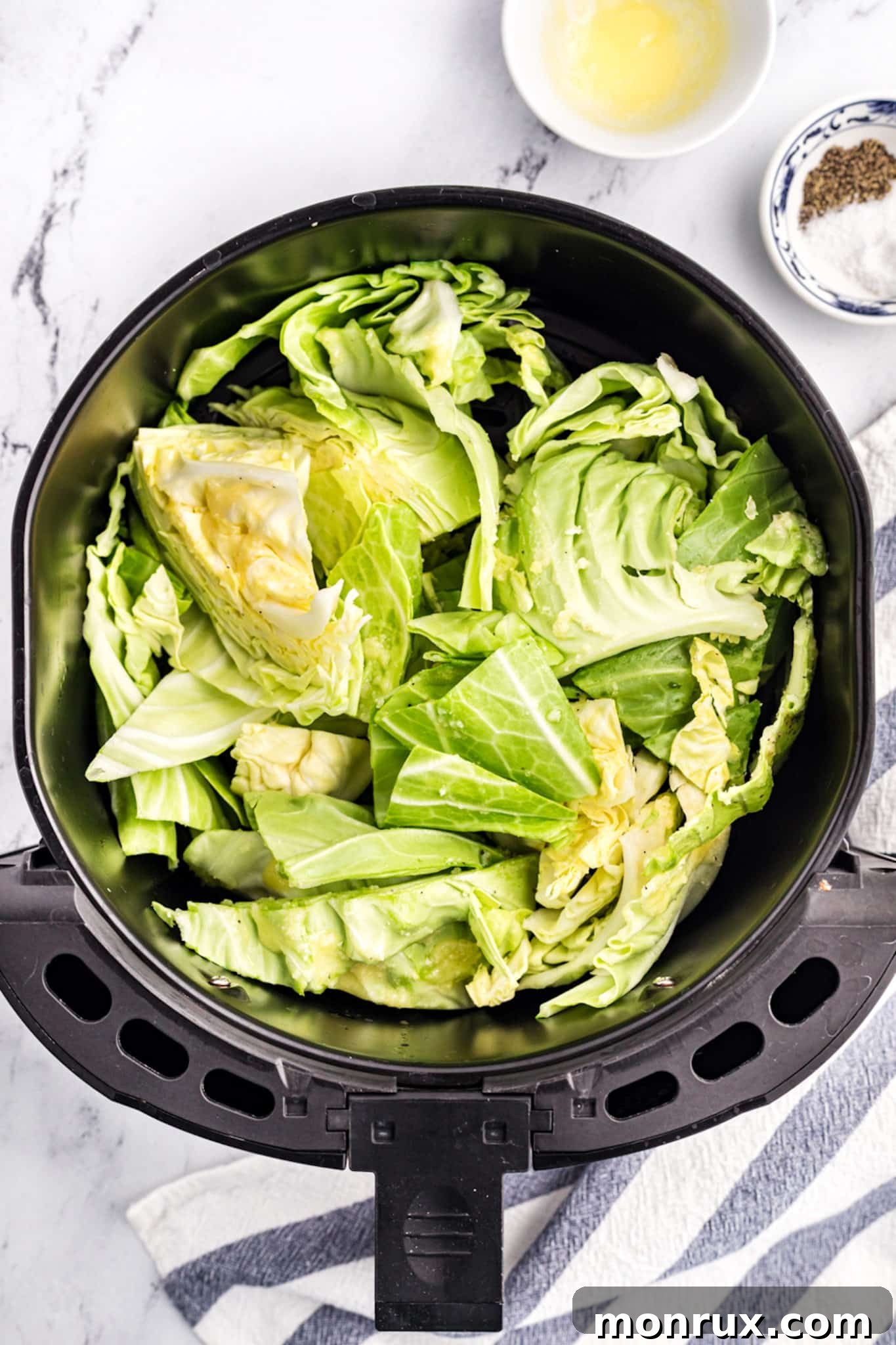 Freshly seasoned cabbage pieces arranged neatly within an air fryer basket, ready for cooking.