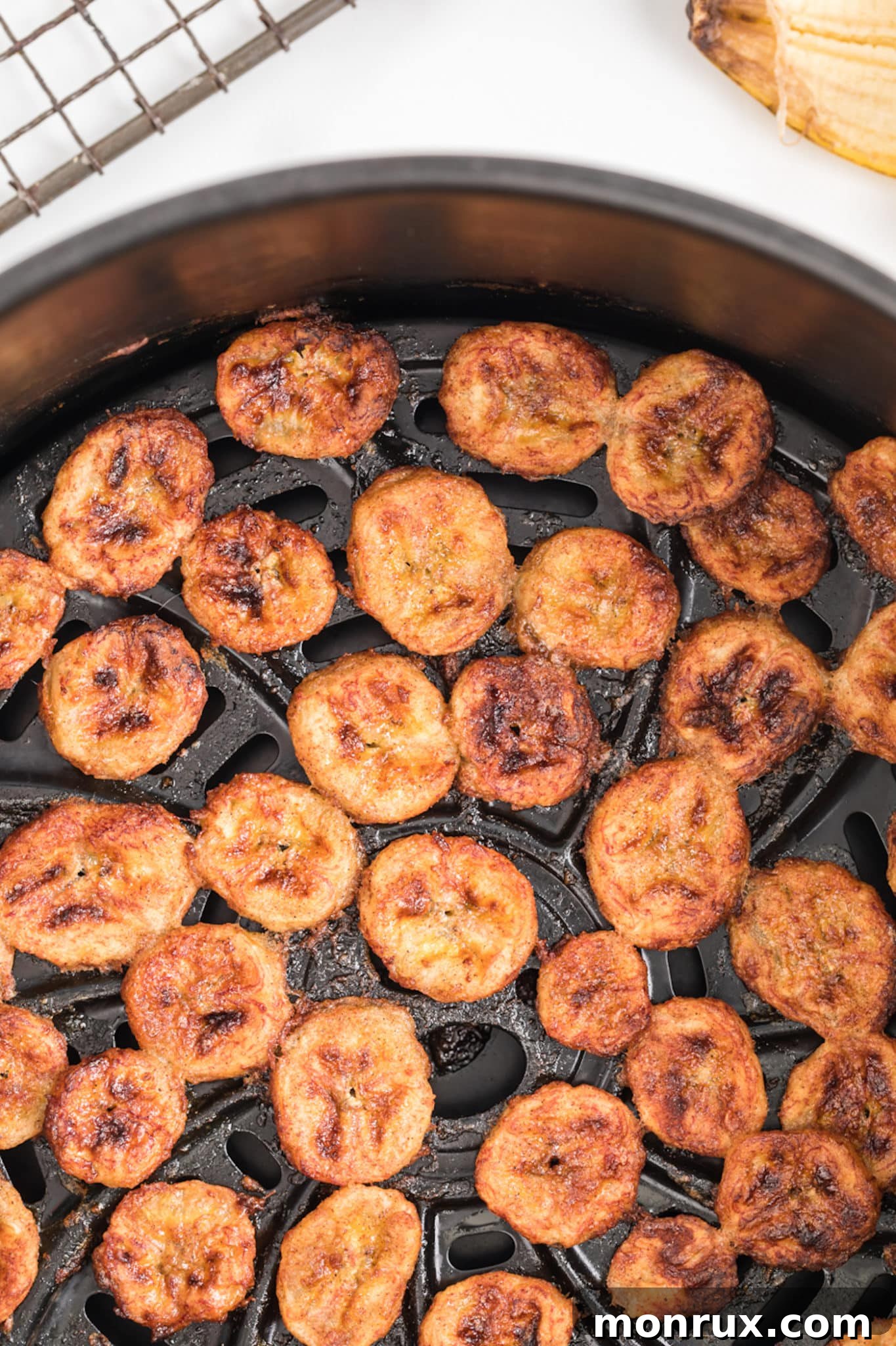 Crispy air fryer banana chips neatly arranged inside the air fryer basket, showing their golden brown color.