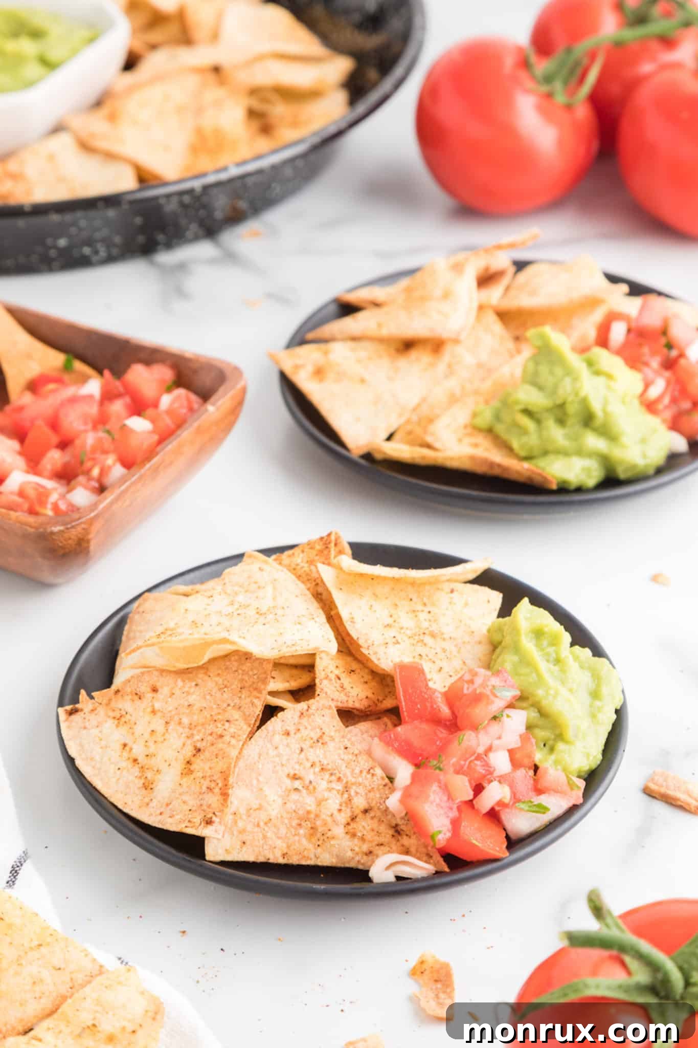 Two small black plates of fresh air fryer tortilla chips with salsa and guacamole.