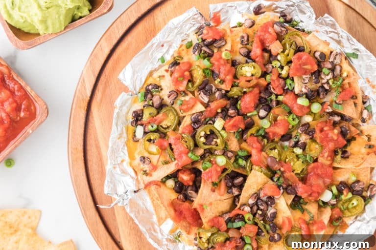 Top view of air fryer nachos on top of a wooden board, garnished with fresh cilantro.