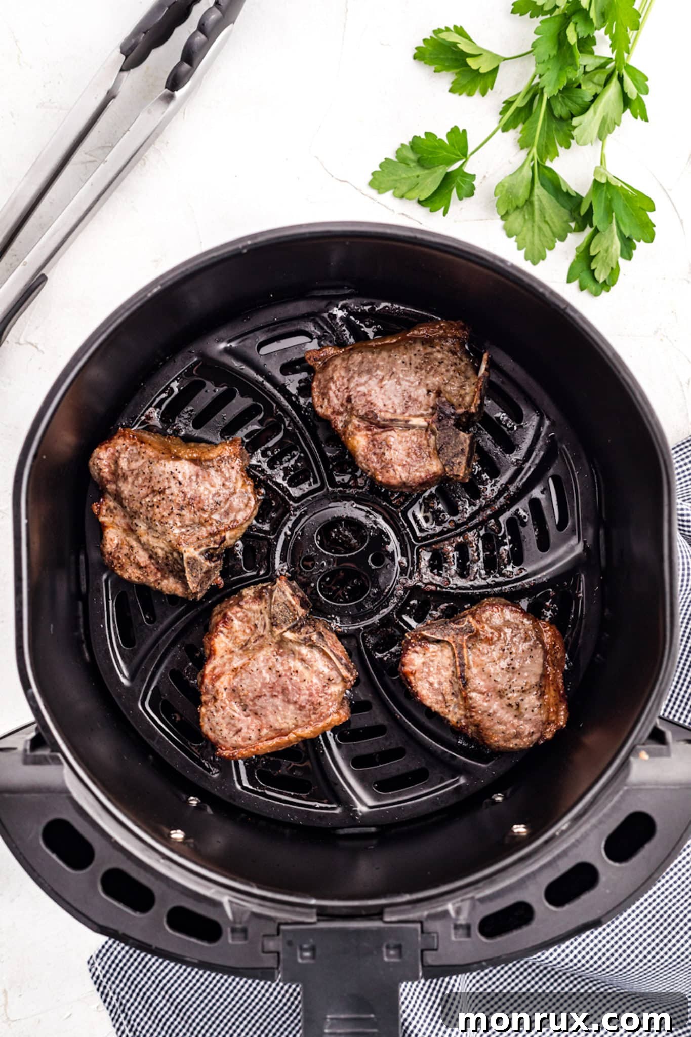 Cooked lamb chops in the basket of an air fryer.