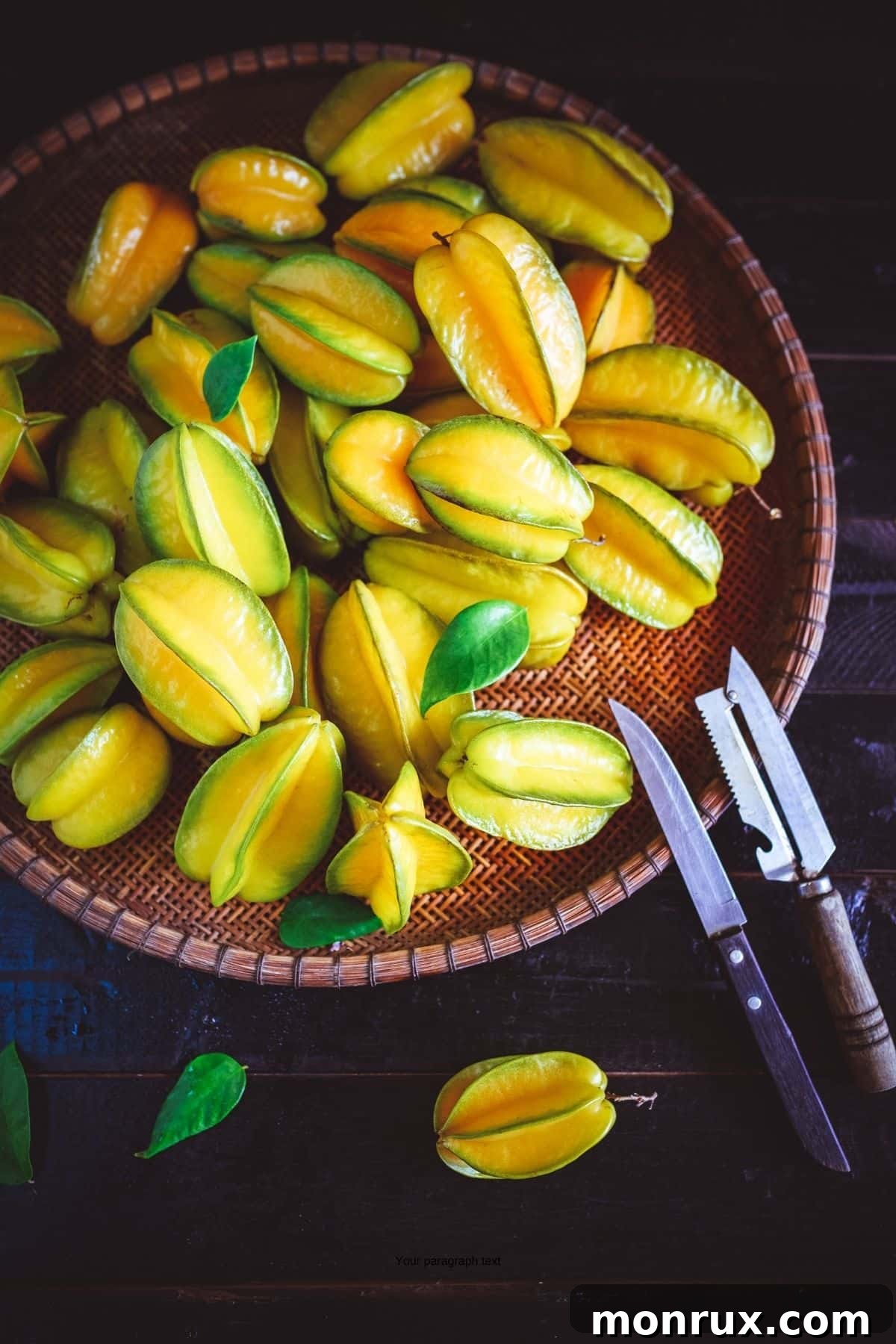 Starfruit in a wood basket with knives next to it.