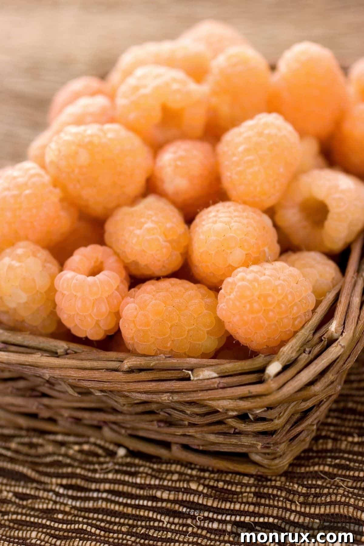 Golden raspberries in a woven basket on a table.