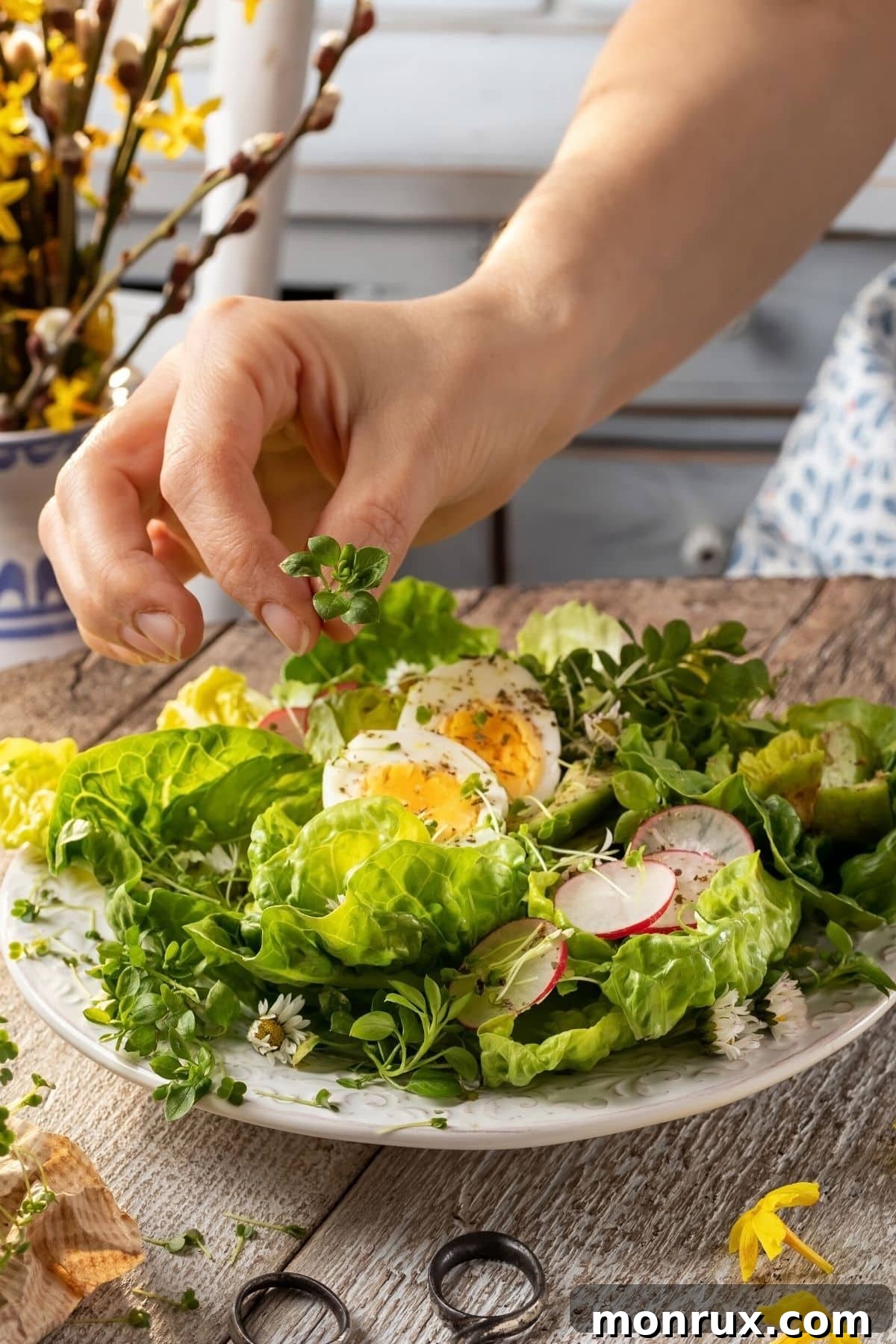 Hands carefully arranging a handful of vibrant microgreens onto a fresh green salad, enhancing its visual appeal and nutritional value.