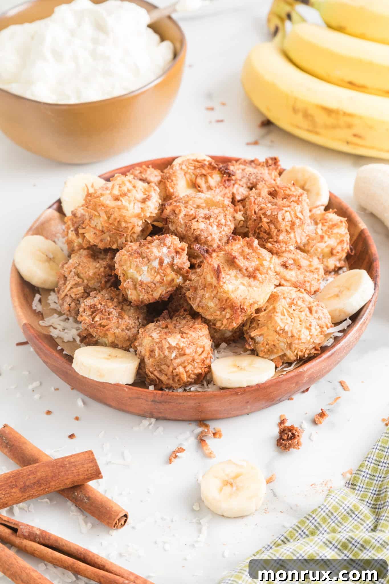 Crispy golden Air Fryer Banana Fritters presented beautifully in a wooden bowl on a pristine white kitchen counter, hinting at their deliciousness and healthy preparation.