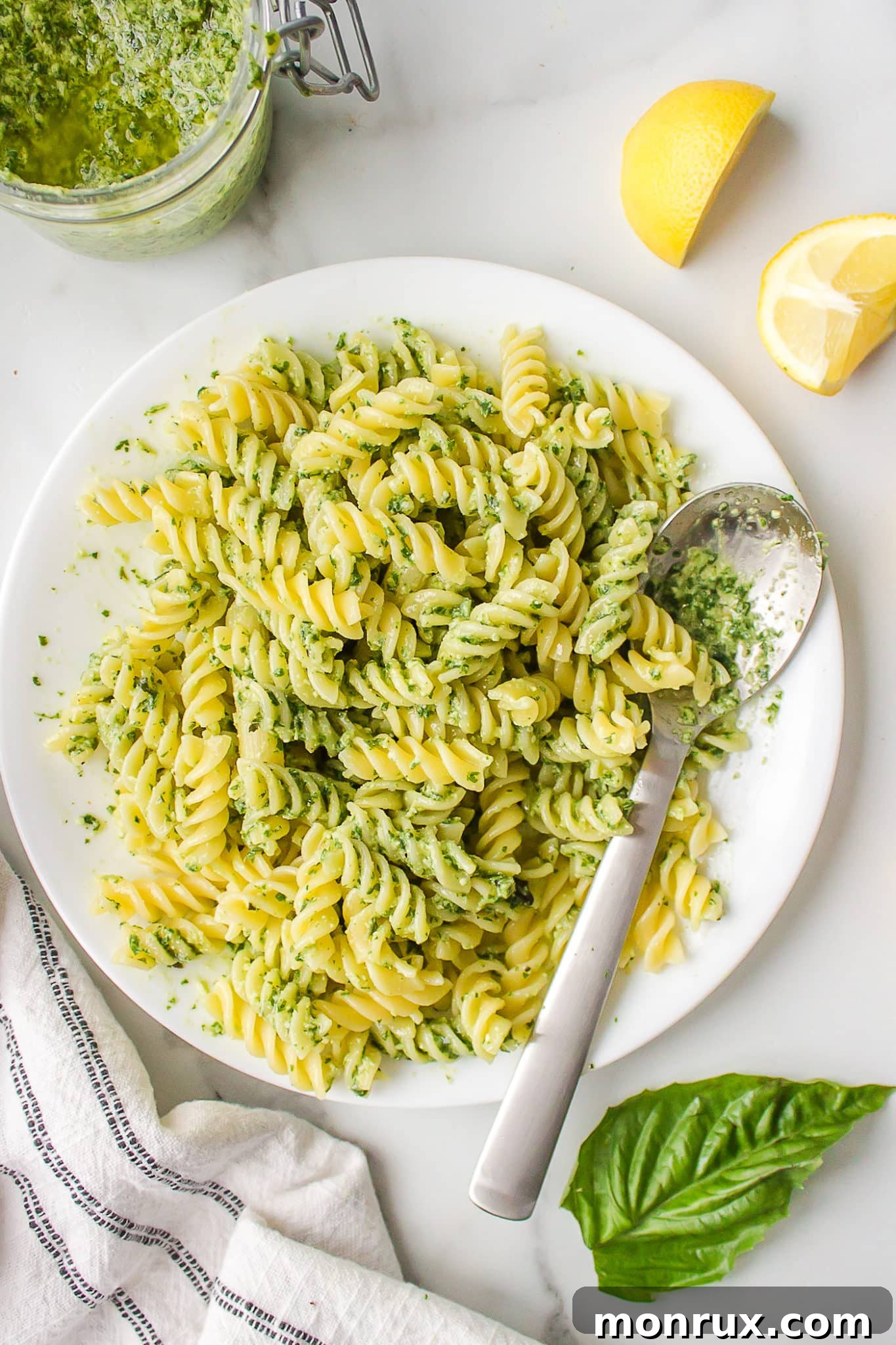 A vibrant bowl of dairy-free pesto pasta made with gluten-free spiral pasta, garnished with fresh basil, ready to be enjoyed.