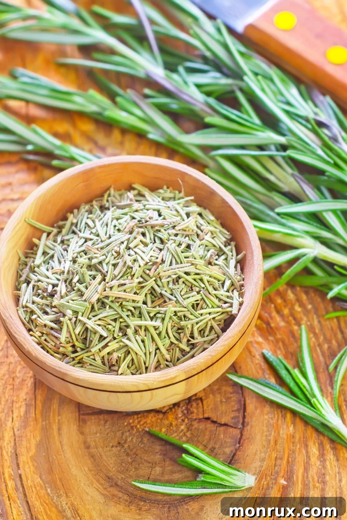 A bowl of dried rosemary next to fresh rosemary sprigs.