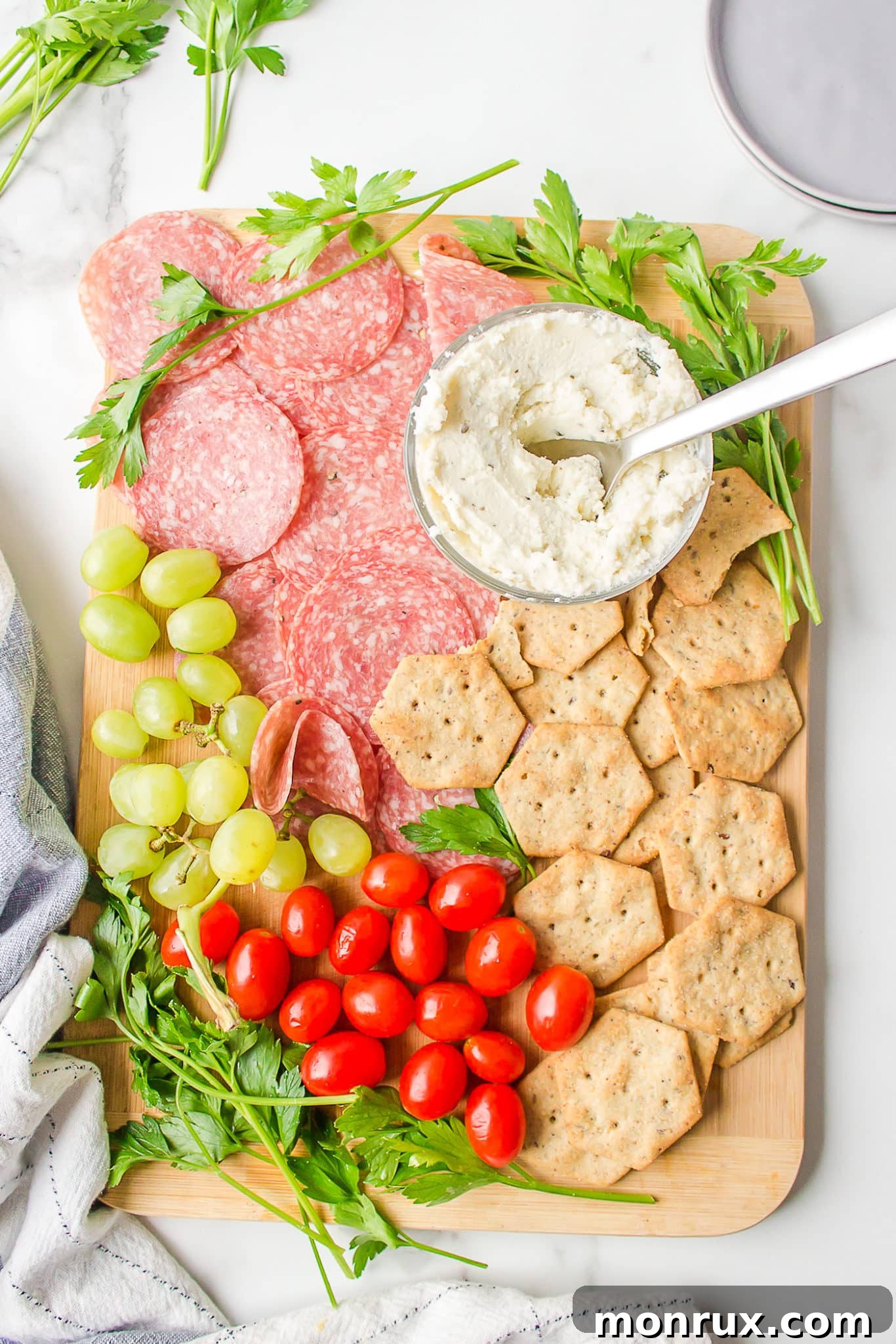A vibrant gluten-free and dairy-free charcuterie board overflowing with grapes, cherry tomatoes, plant-based cheese, and cured meats, perfect for any gathering.