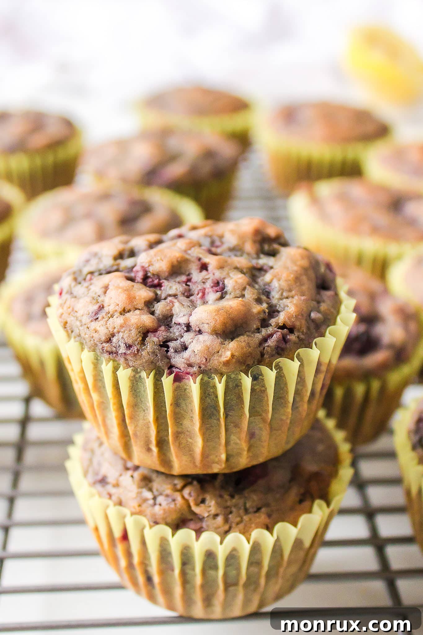 Vegan blackberry muffins in yellow papers on a metal cooling rack.