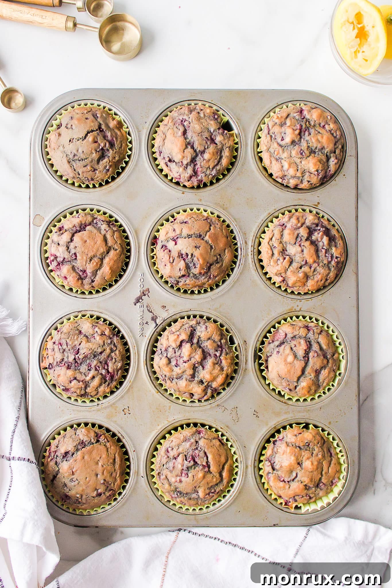 Baked vegan blackberry muffins in yellow papers in a muffin tin.