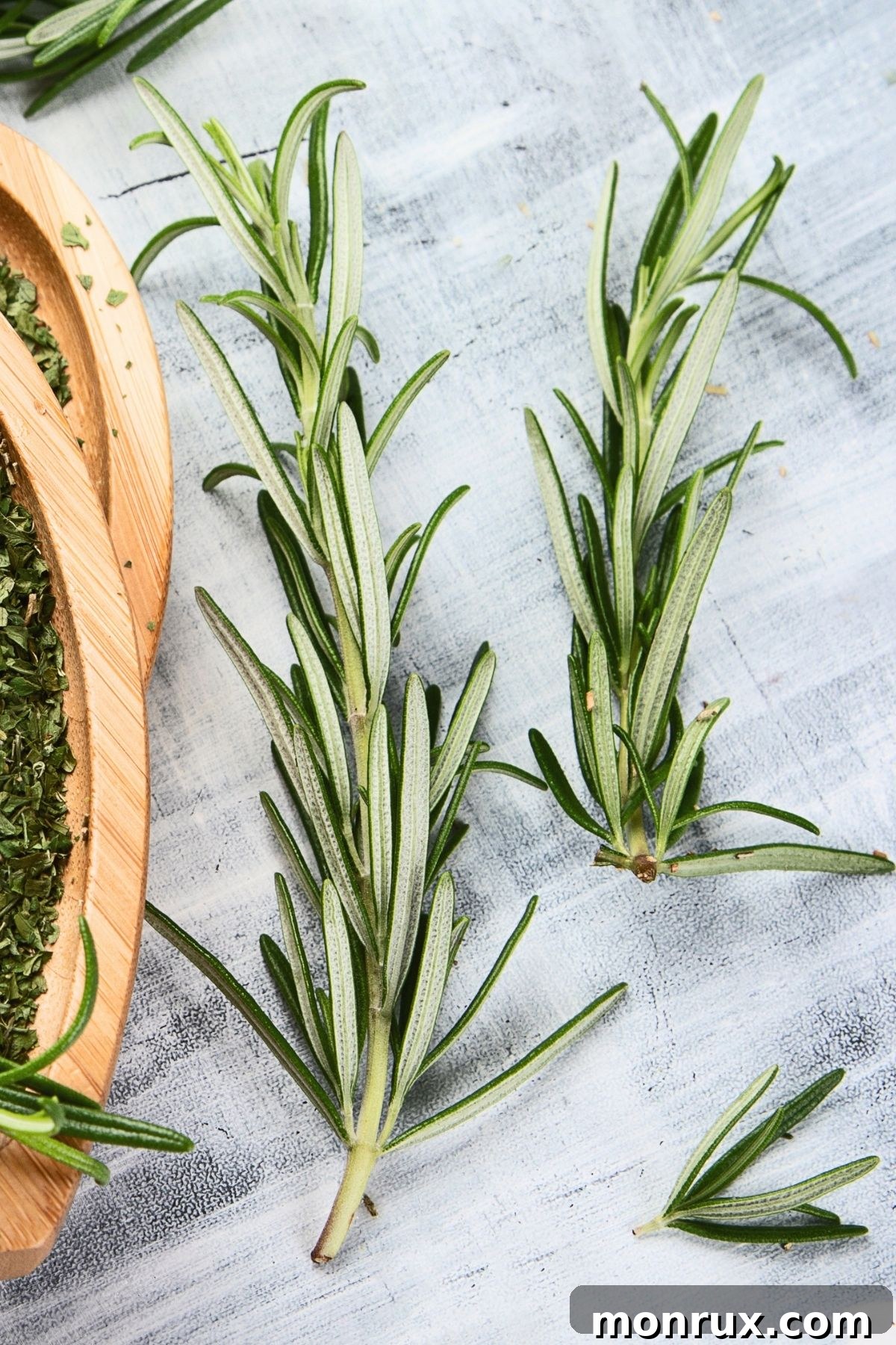 Fresh rosemary sprigs on a white surface.