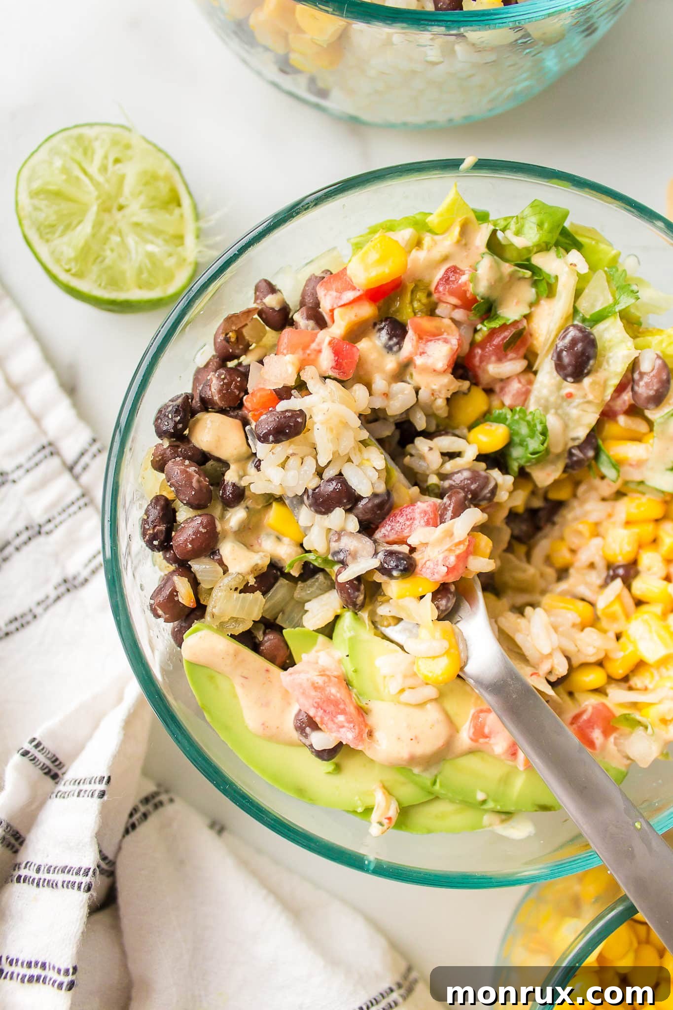 A beautifully presented Mexican brown rice Buddha bowl in a clear glass, showing off its fresh and vibrant components.