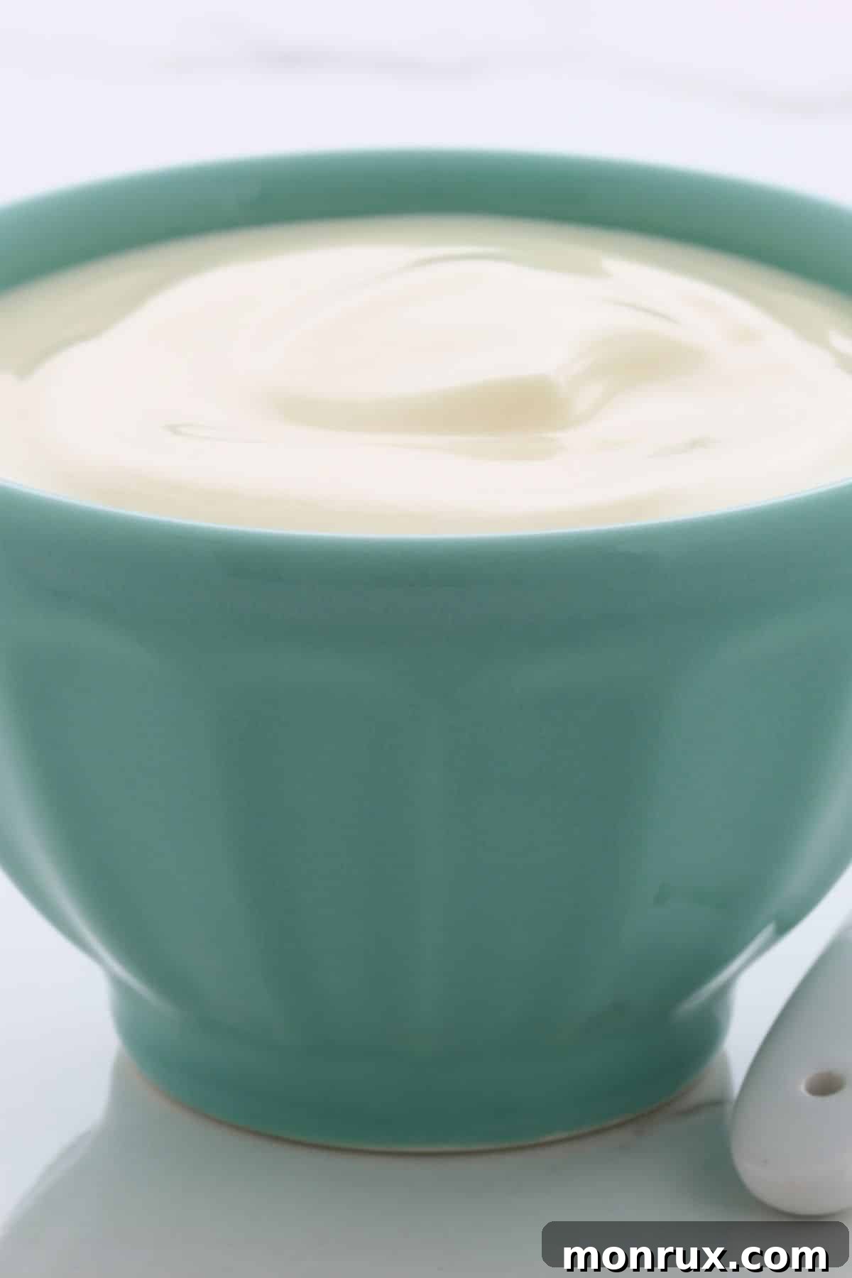 Small green bowl filled with plain yogurt, suggesting probiotic richness.