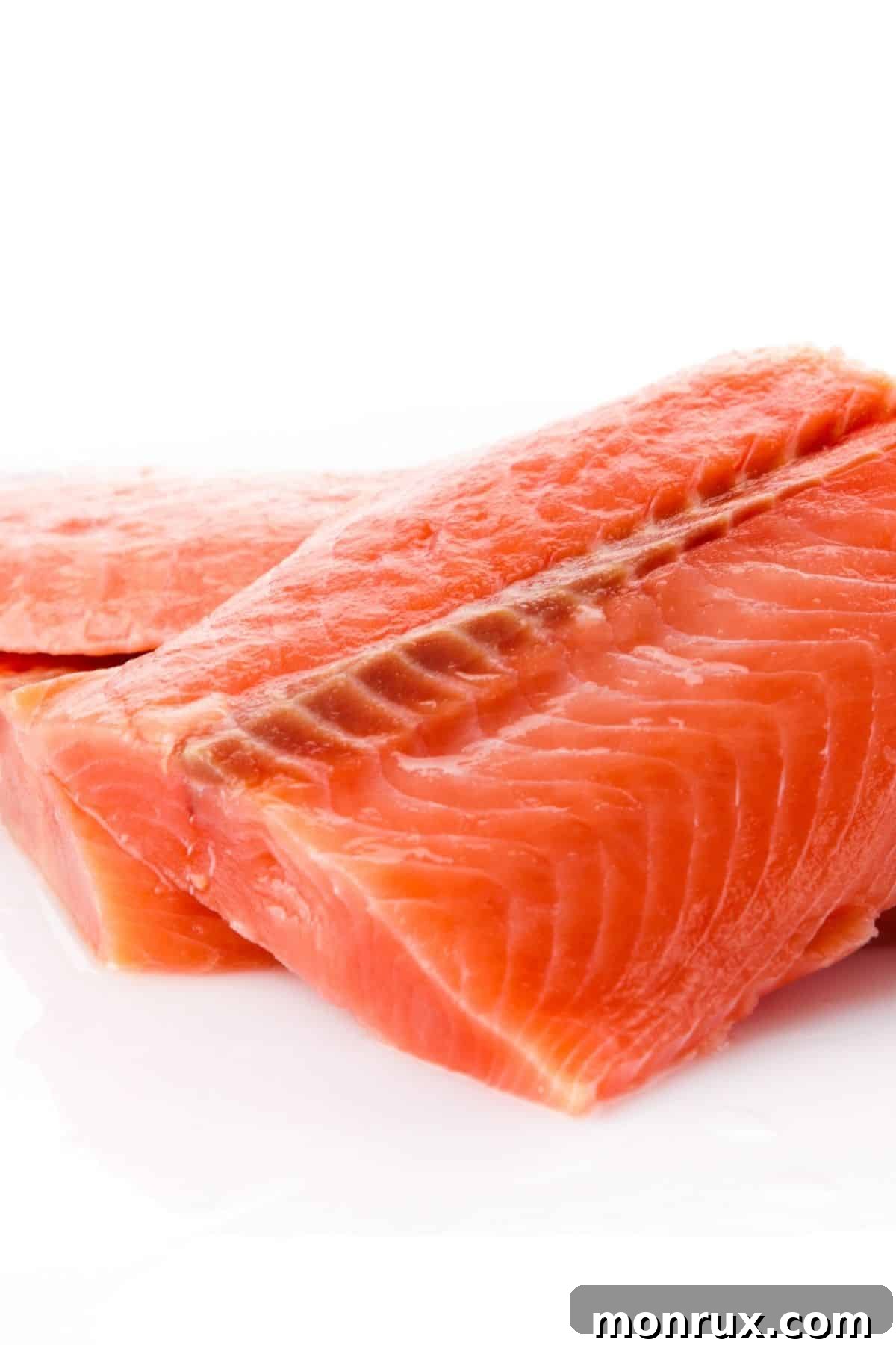 Raw salmon fillets neatly arranged on a pristine white surface.