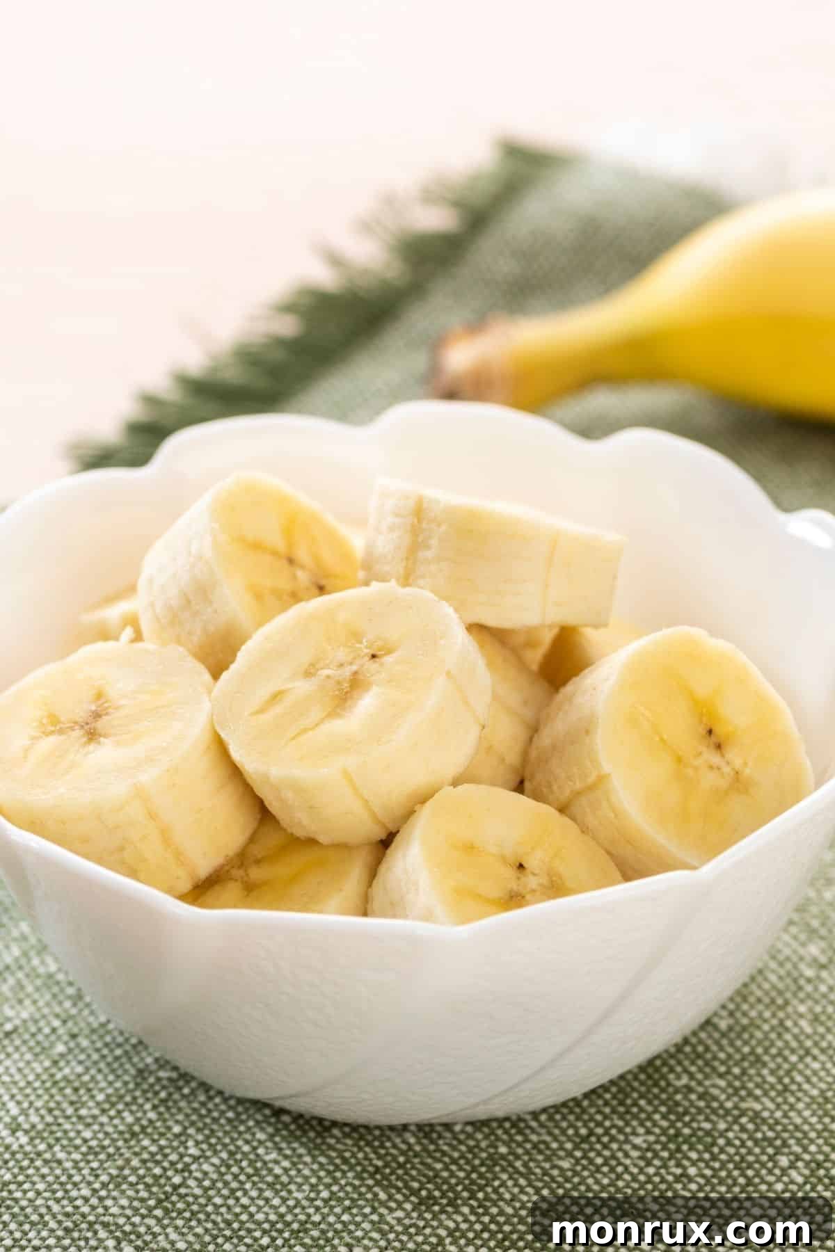 A small white bowl filled with freshly sliced banana.