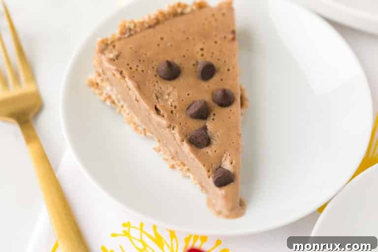 A stunning slice of vegan peanut butter pie served on a pristine plate with a gleaming gold fork, highlighting its rich texture and tempting layers.