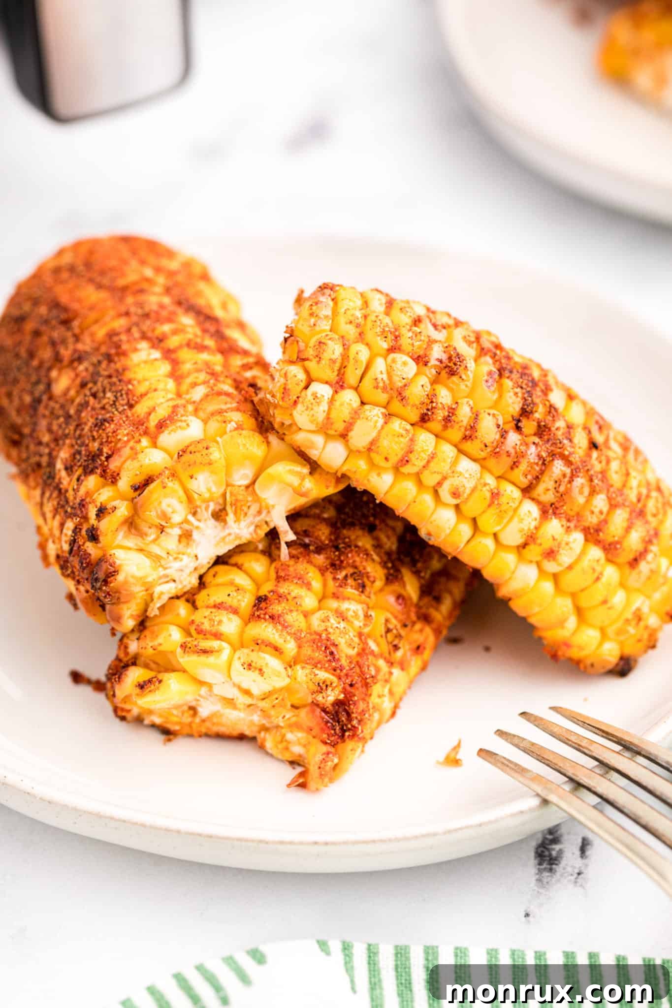 Perfectly air-fried corn ribs on a white plate, garnished and ready to be enjoyed as a summer side.