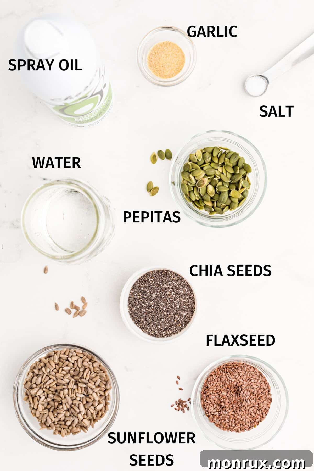 Various raw seeds—chia, flax, sunflower, and pumpkin—arranged in small bowls on a clean white surface, ready for making crackers.