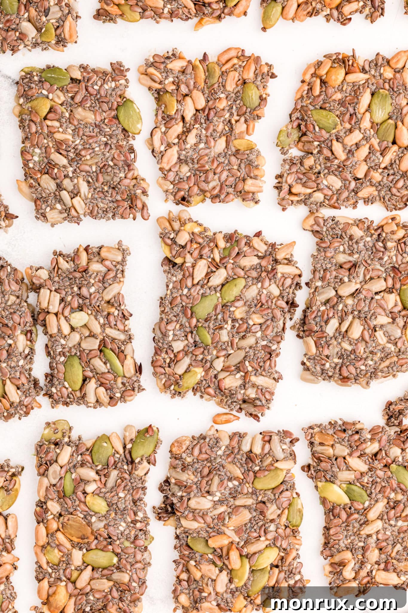 Deliciously baked seed crackers resting on parchment paper after cooling, showcasing their rustic appeal.