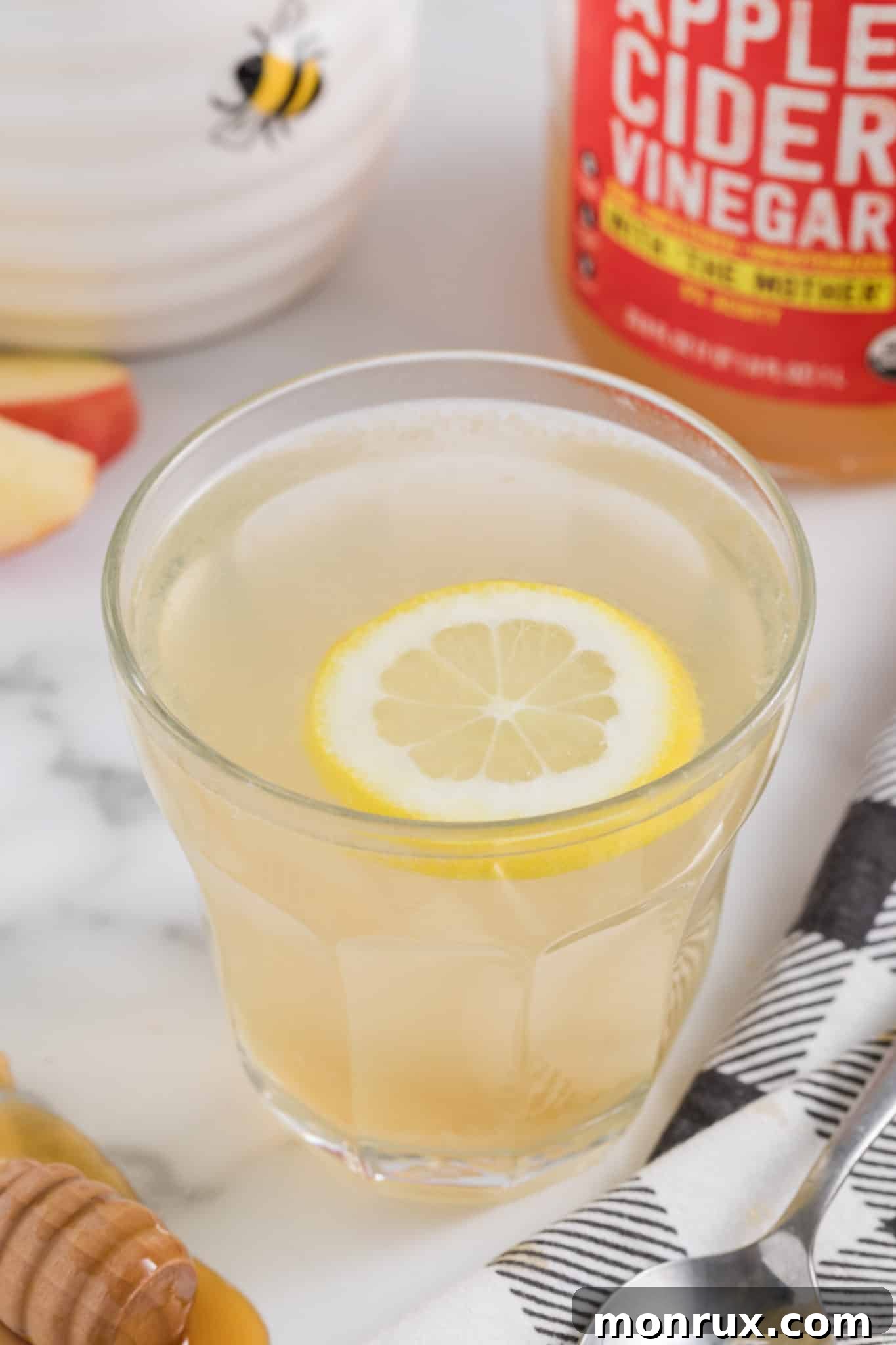 Apple cider vinegar drink in a glass with a floating lemon wheel, ready to be enjoyed as a refreshing start to the day.