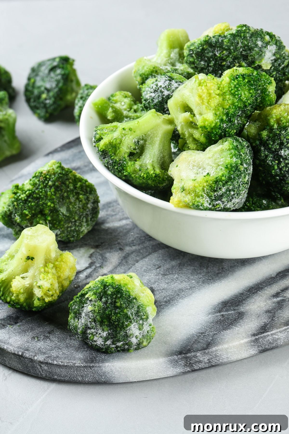 A bowl filled with small, perfectly frozen broccoli florets, ready for cooking or blending.