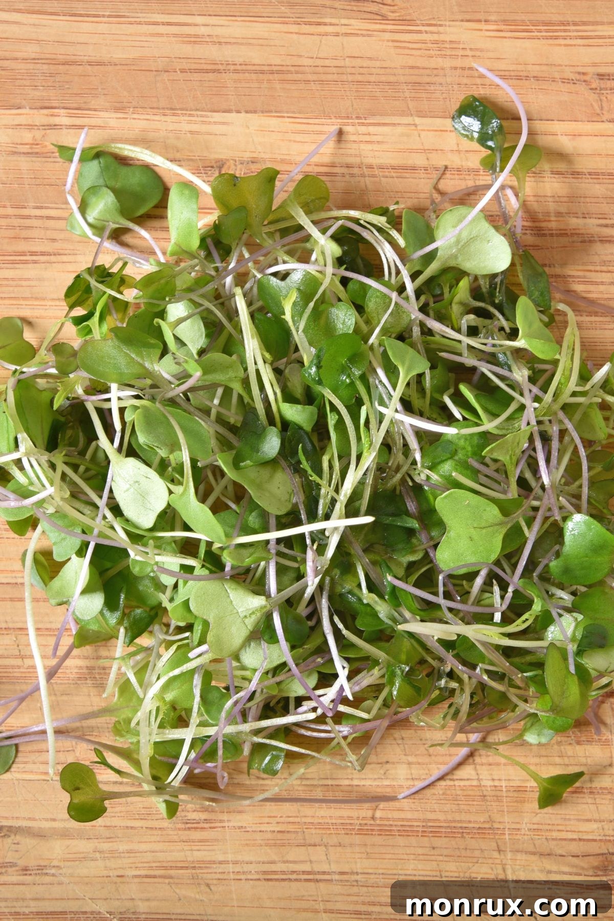 A vibrant selection of microgreens arranged on a wooden cutting board, showcasing their delicate forms.