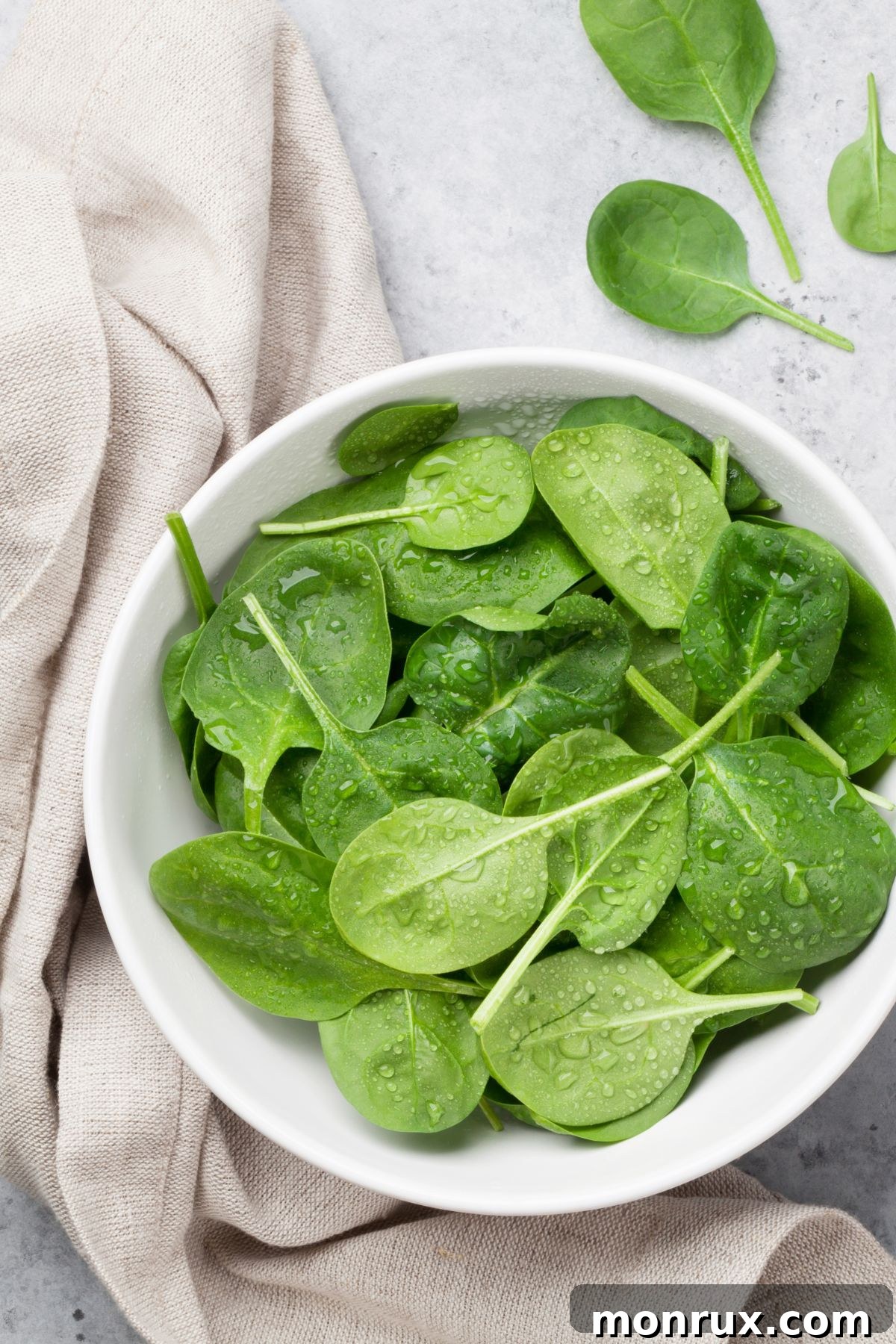 A bowl filled with fresh, vibrant baby spinach leaves, ready for use in a smoothie.