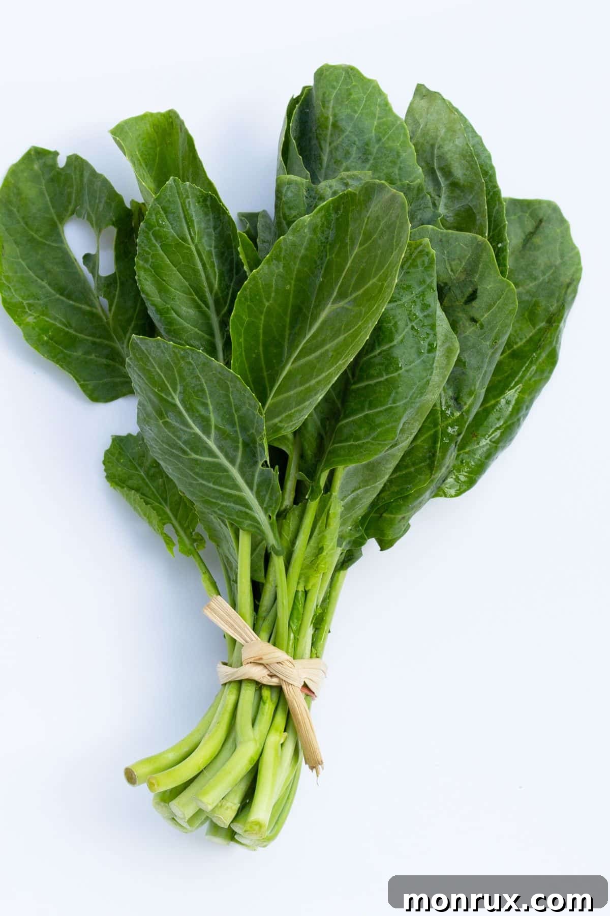 A fresh, vibrant bunch of collard greens, ready for culinary use, displayed on a clean surface.
