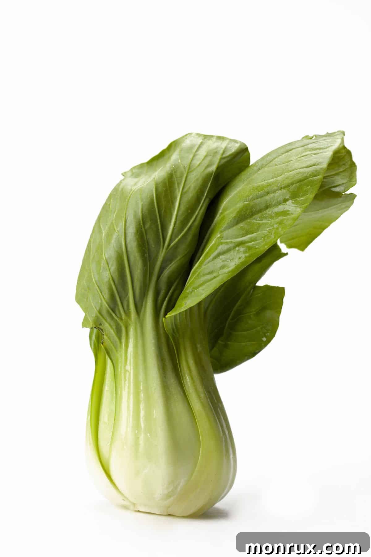 Fresh, crisp bok choy leaves arranged neatly on a wooden table, highlighting their vibrant green and white stalks.