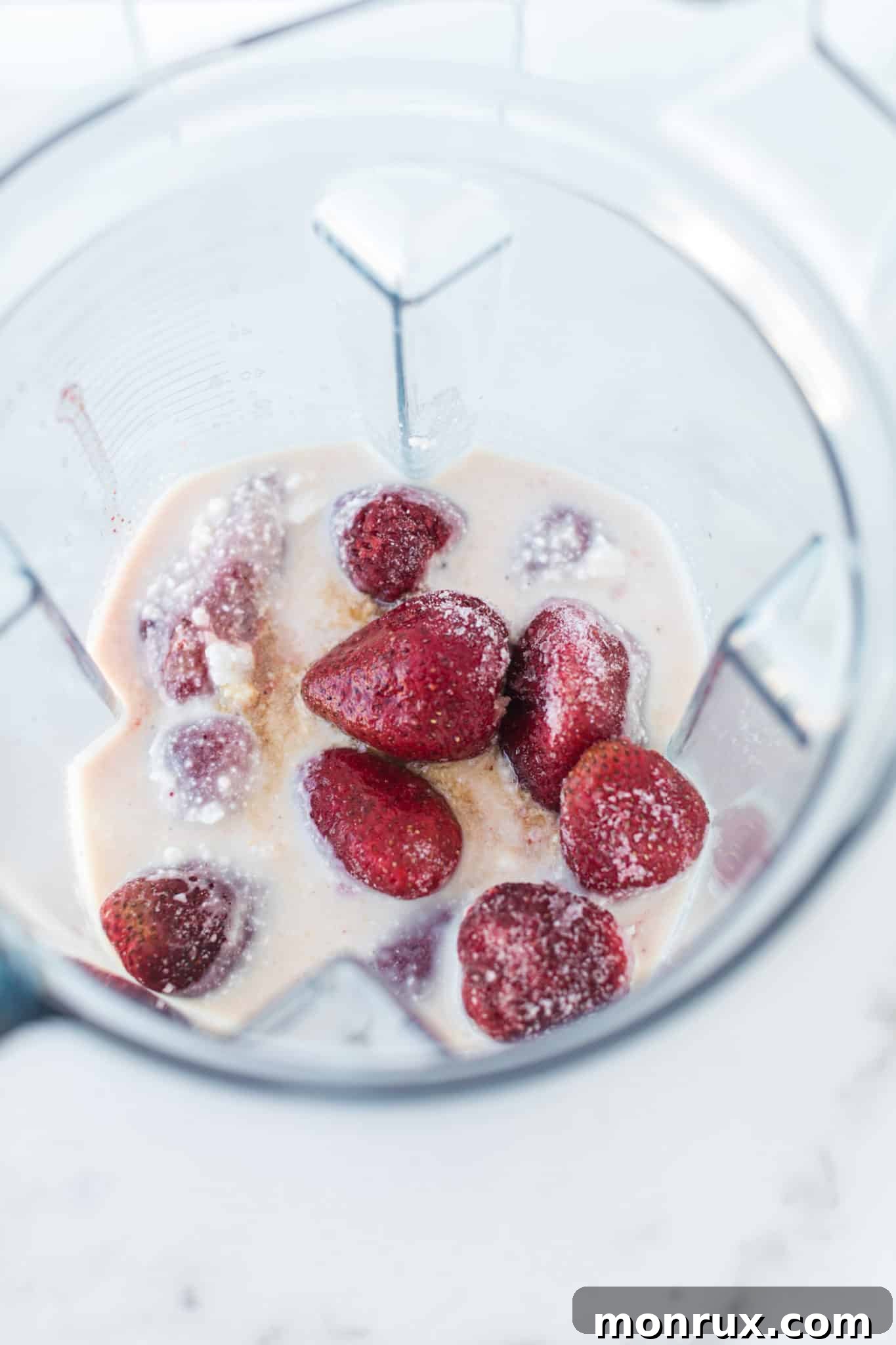 Strawberries and coconut milk being blended in a Vitamix blender.