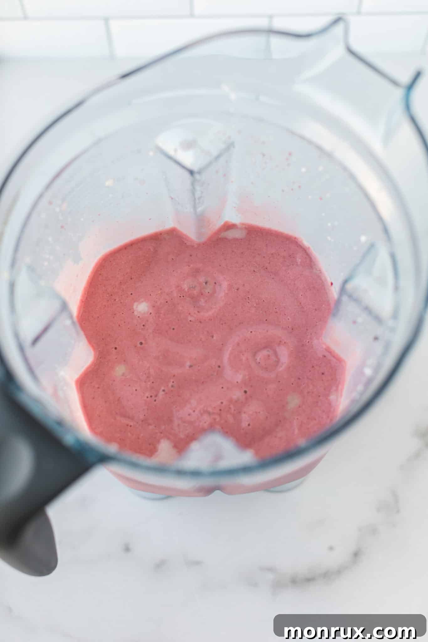Blended strawberry ice cream base in a blender, showing a smooth, pink consistency.