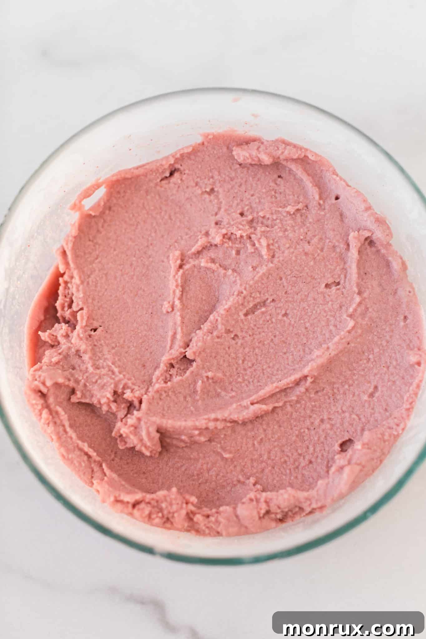 A bowl of firm, frozen vegan strawberry ice cream, ready to be served.