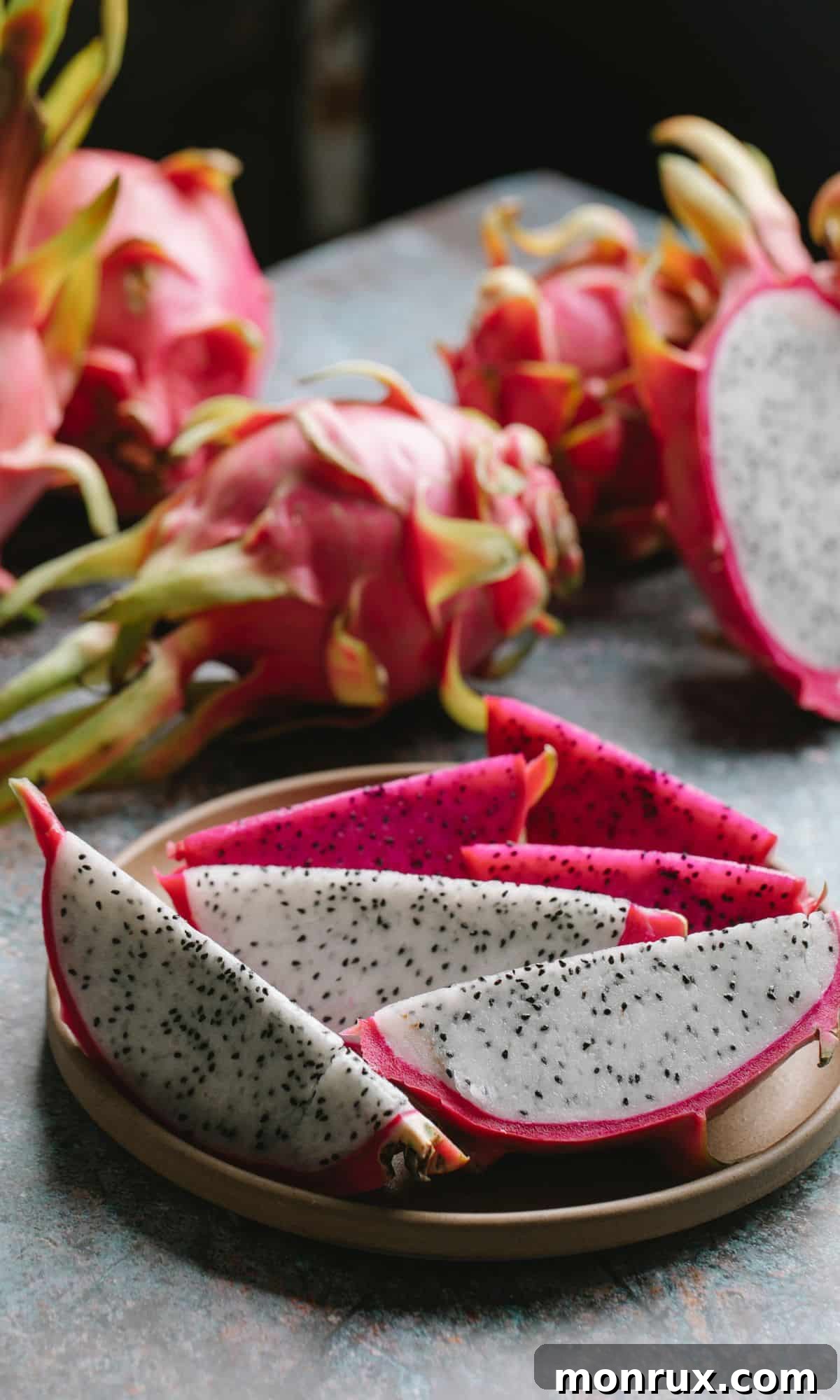 A vibrant dragon fruit, sliced to reveal its speckled white flesh.