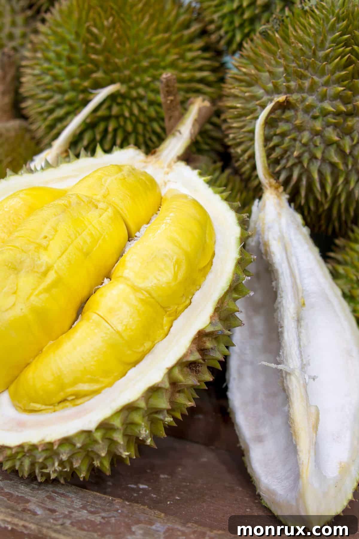 A thorny durian fruit cut in half to show its creamy flesh.