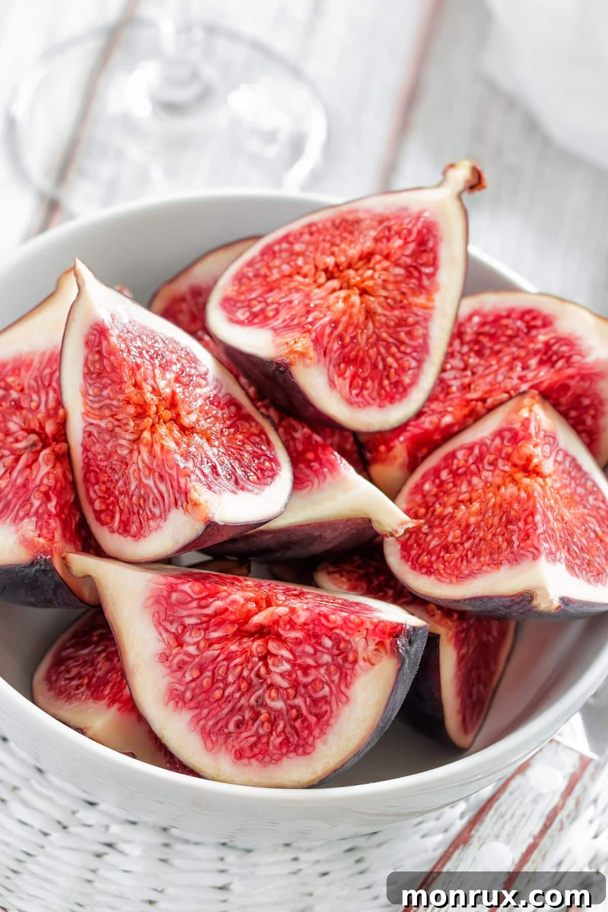 A white bowl showcasing quartered fresh figs.