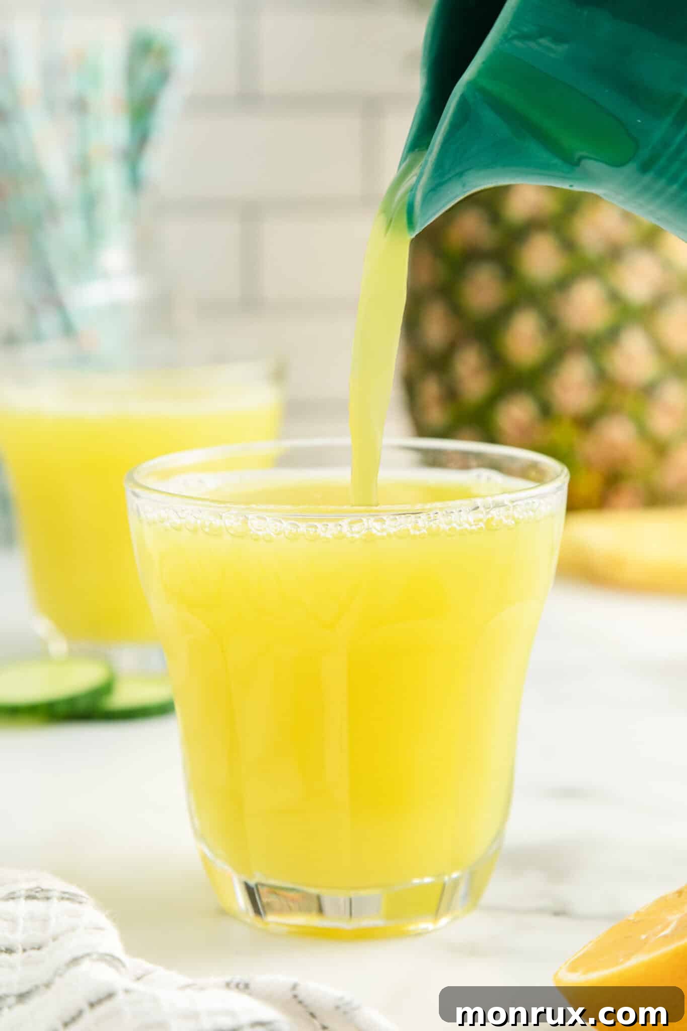 pouring pineapple cucumber juice into a glass.