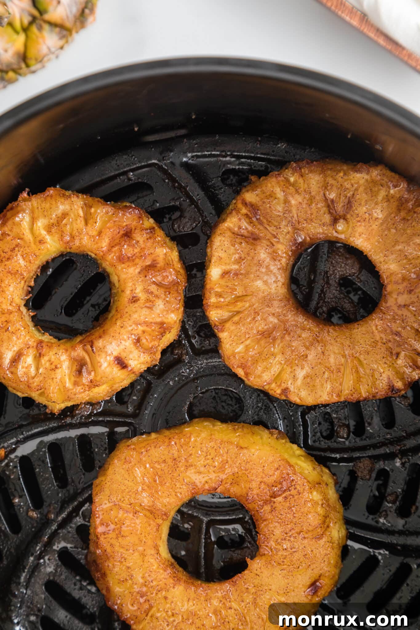 Air fried pineapple rings in the basket of an air fryer.