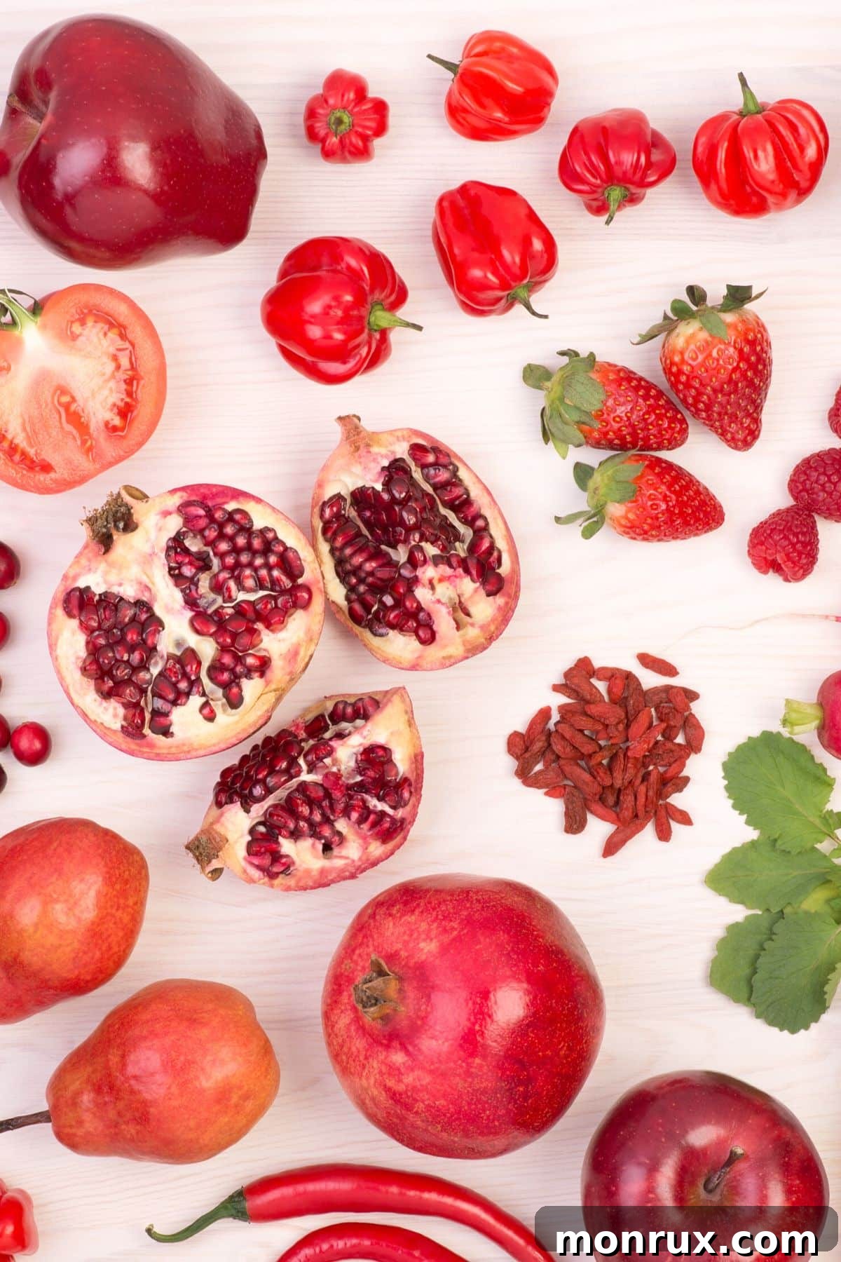 Assortment of vibrant red fruits including strawberries, raspberries, and cherries beautifully arranged on a rustic wooden table, showcasing their fresh appeal and rich colors.