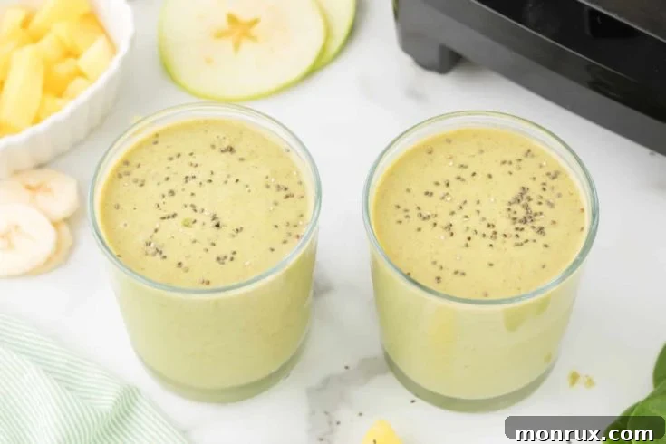 Spinach and green apple smoothie in a glass with a straw.