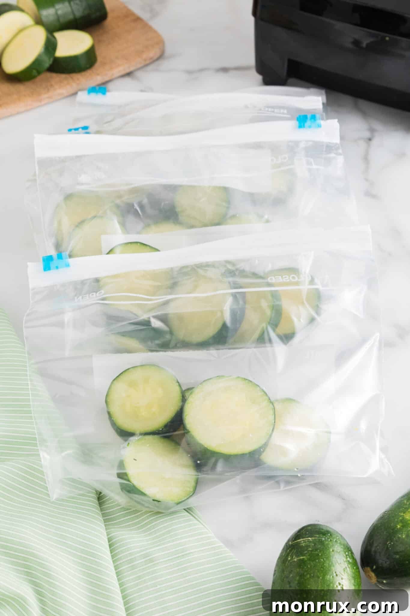 Small freezer-safe bags filled with frozen zucchini rounds, neatly stacked on a kitchen counter.