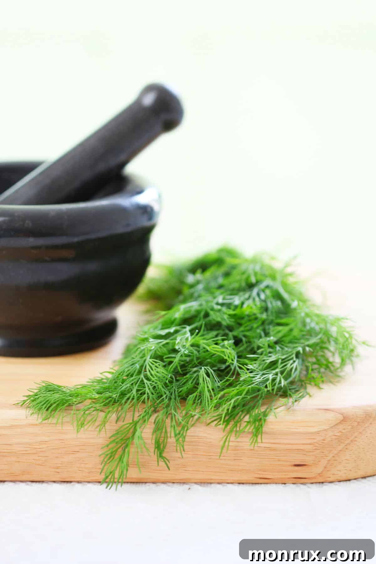 Cutting board with fresh dill and mortar and pestle, highlighting dill as a versatile herb.