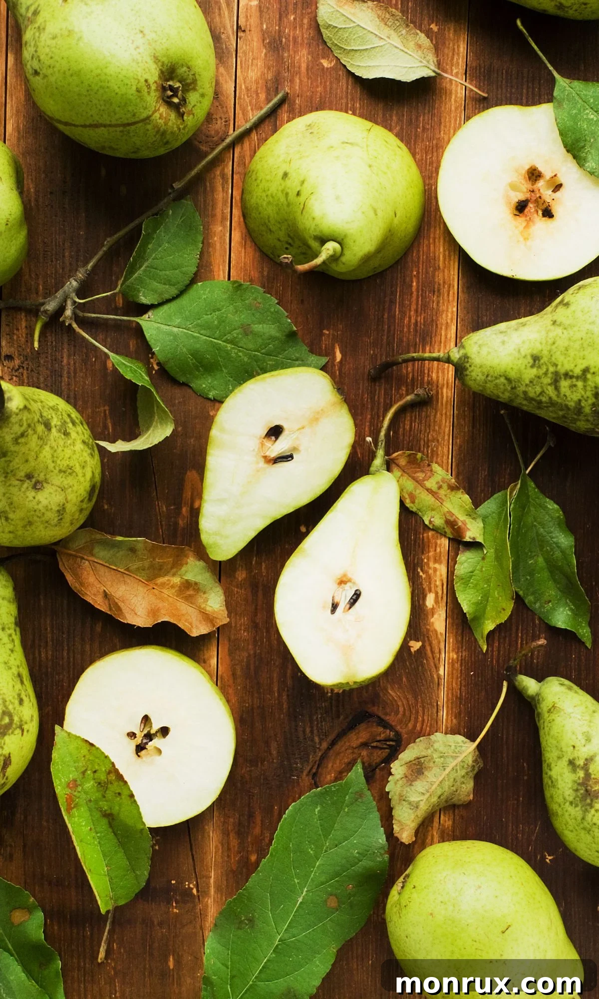 Many fresh green pears displayed on a rustic wooden table.