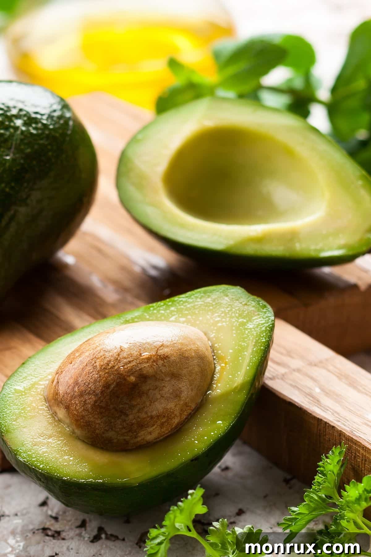 avocado cut in half on table, showing its creamy green flesh and large pit.