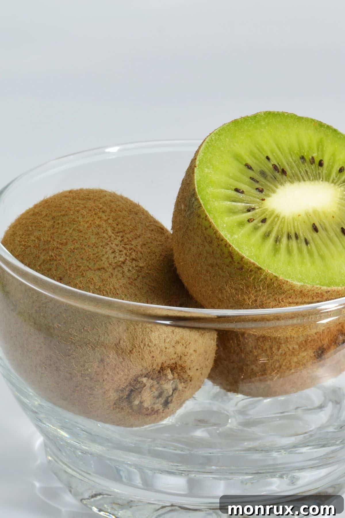 Fresh kiwi fruit, sliced and whole, presented in a small glass bowl.