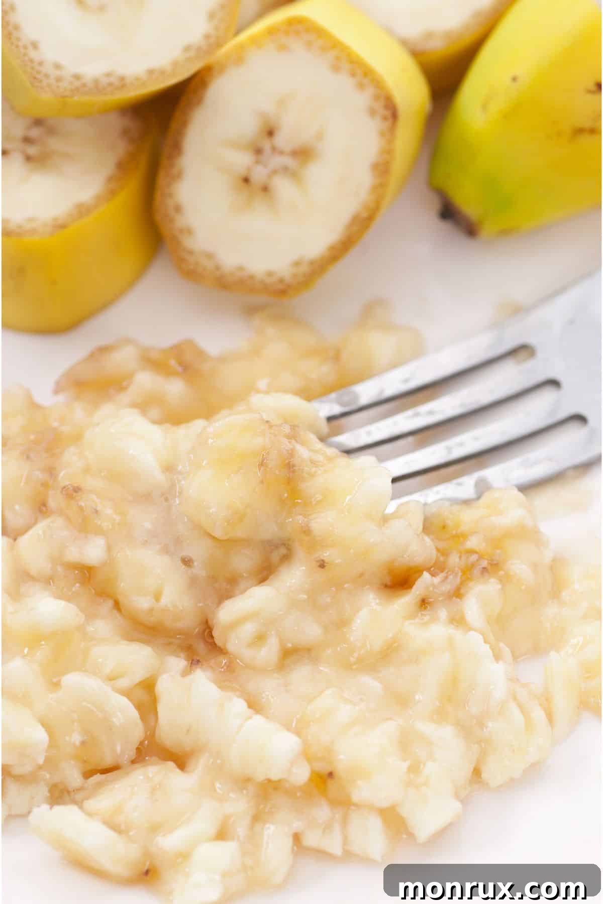 Fork-mashed banana next to sliced bananas.