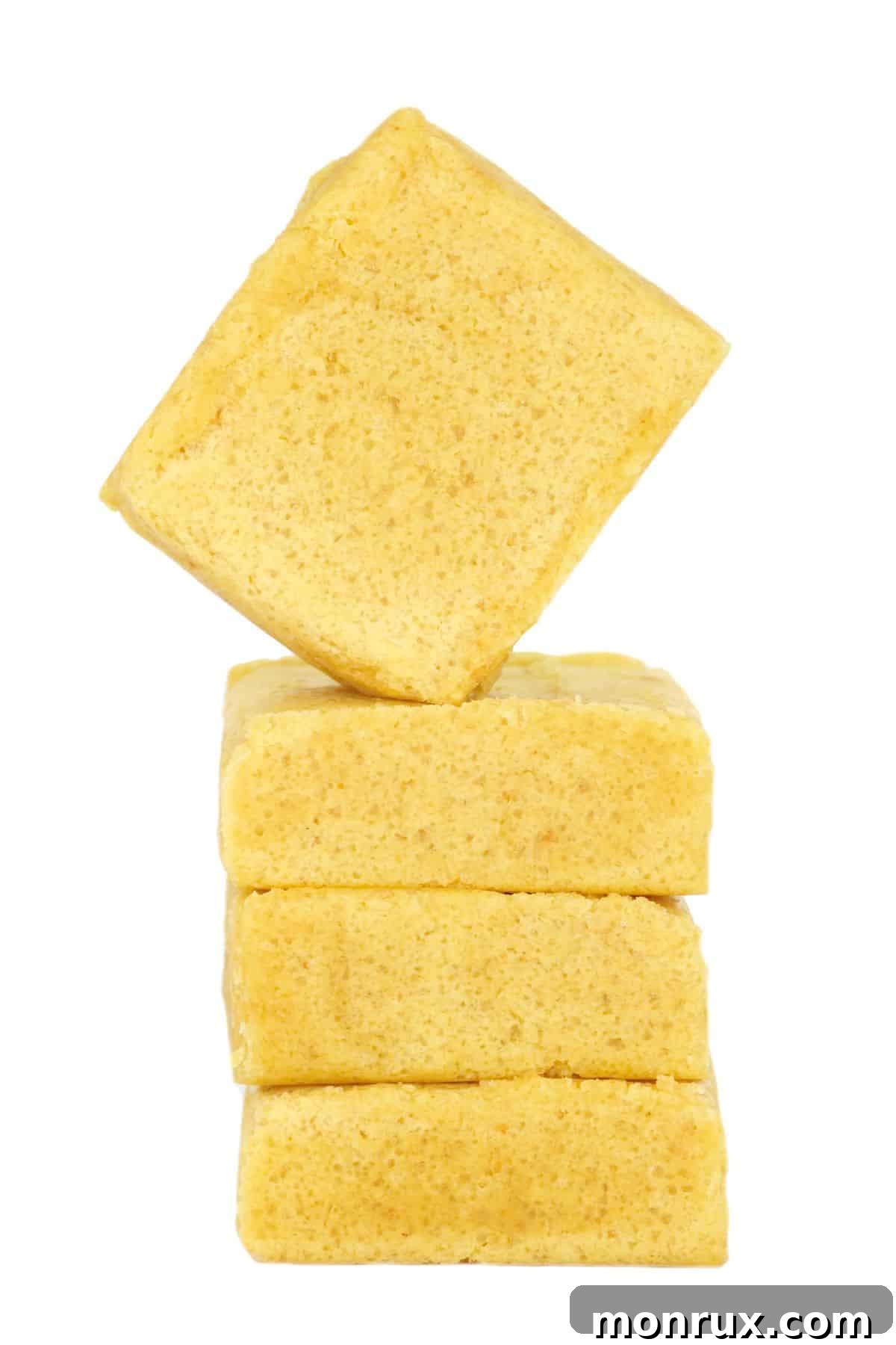 A stack of beef bouillon cubes next to a measuring spoon of bouillon granules.